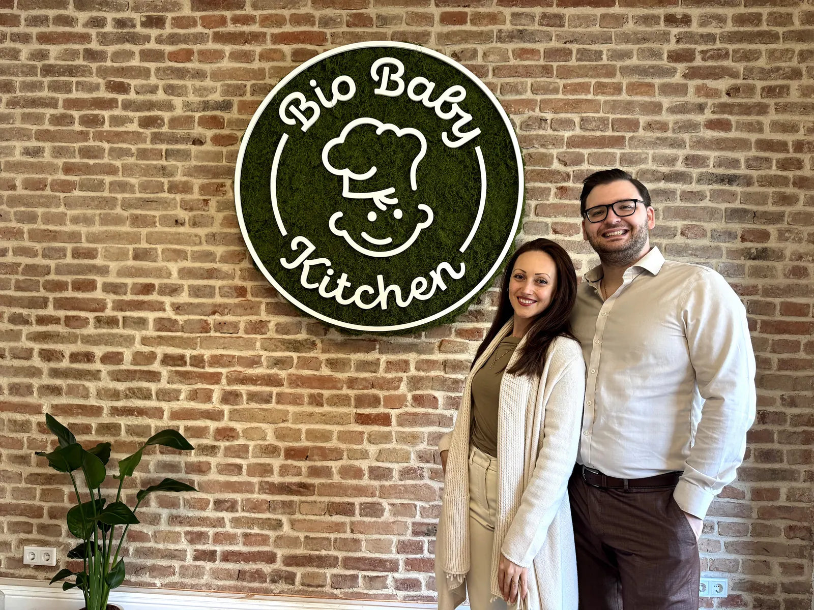 Georgi und Stiliyana, Gründer:innen von Bio Baby Kitchen, vor ihrem Logo in Frankfurt
